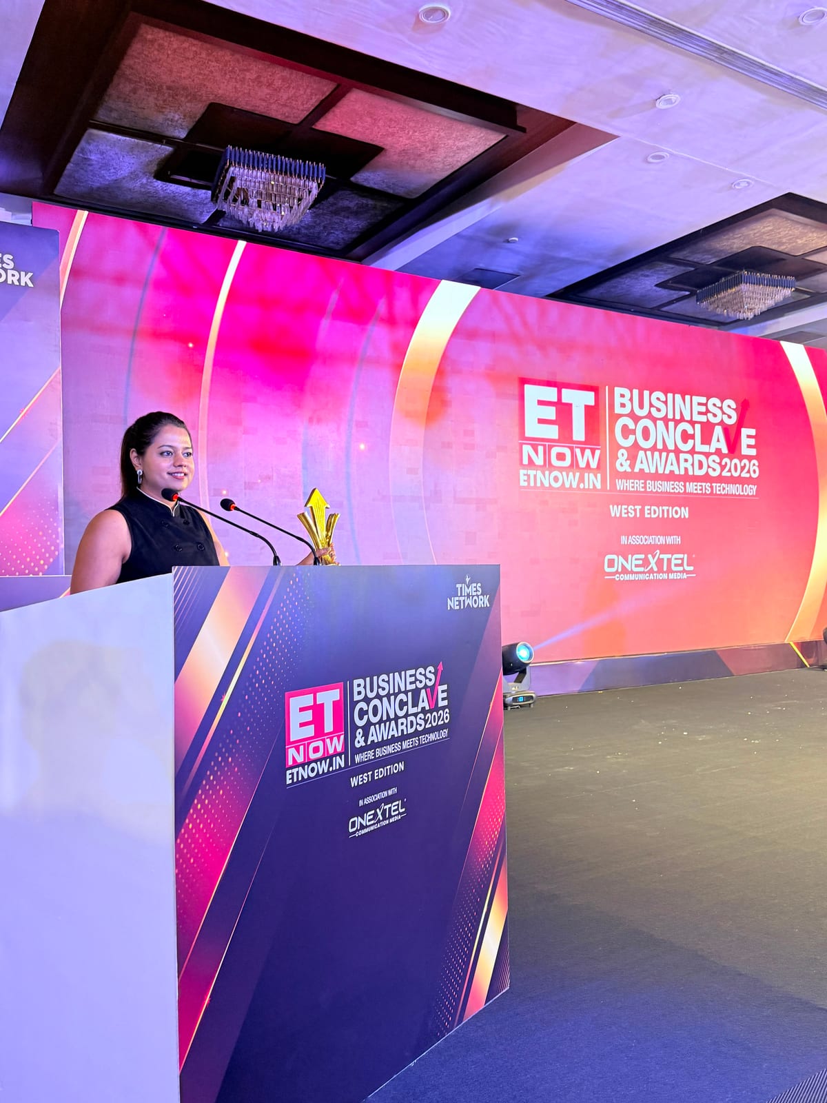 Shivani Tikadia speaking at the podium with the trophy, ETNOW.in Business Conclave and Awards 2026, West Edition, Mumbai