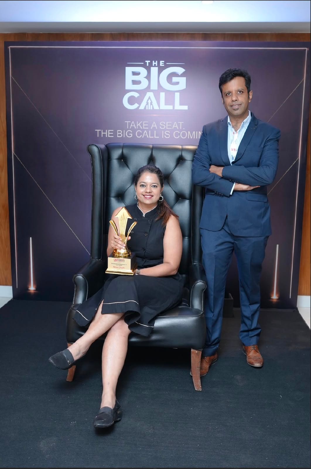 Shivani Tikadia seated with a trophy at The Big Call photo area alongside a SecComply colleague
