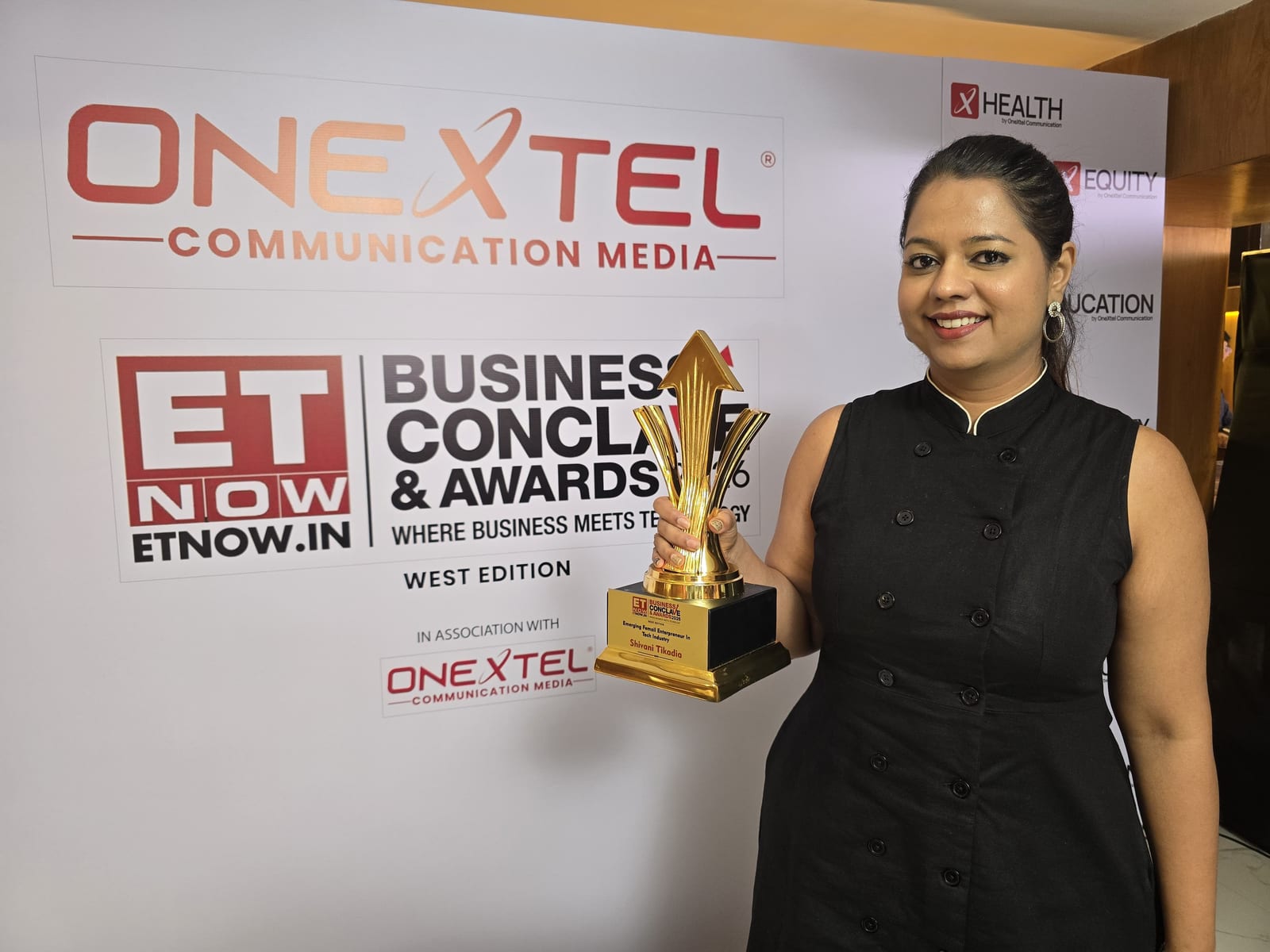Shivani Tikadia with the trophy beside the ETNOW.in and OneXtel branding at the West Edition in Mumbai